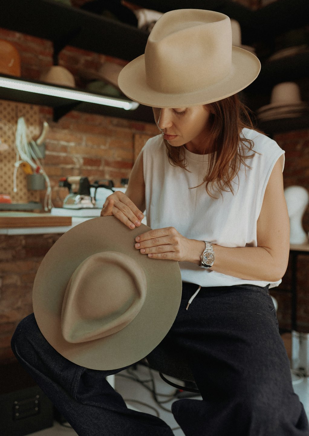 An artisan shapes a felt fedora in her workshop.